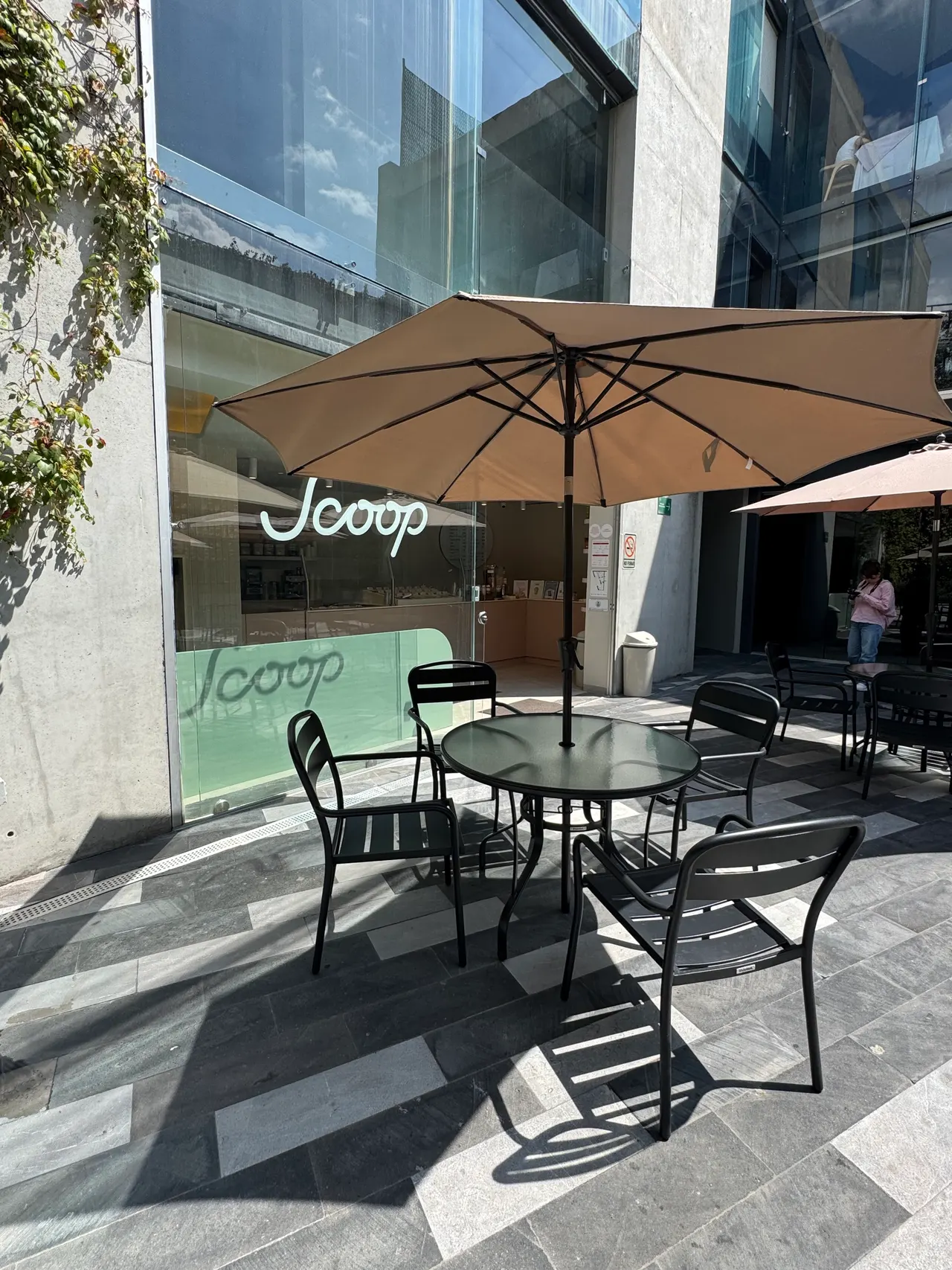 Terraza frente a Scoop con mesas a la sombra de una sombrilla